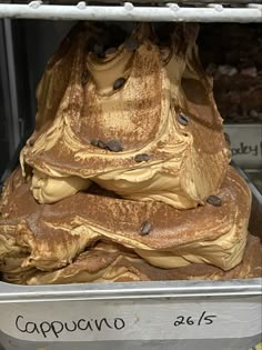 a pile of chocolate covered donuts sitting on top of a metal tray in a store