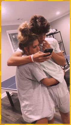 two people hugging each other in front of a ping pong table