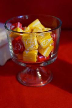 a glass bowl filled with candy sitting on top of a red table