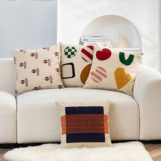 a white couch with colorful pillows on top of it and a rug in front of it