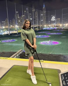 a woman standing on top of a green field holding a golf club