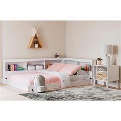 a white bed with pink sheets and pillows in a room next to a book shelf