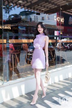 a woman standing in front of a store window wearing a purple dress and high heels