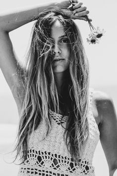 black and white photograph of woman with flowers in her hair, wearing crochet top