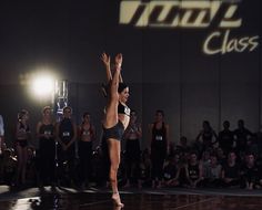 a woman standing on top of a dance floor in front of a group of people