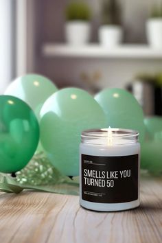 a candle sitting on top of a wooden table next to balloons and green balls in the background