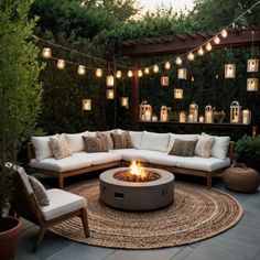 a fire pit surrounded by seating and lights in an outdoor space with potted plants