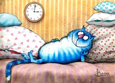 a blue cat laying on top of a bed next to pillows and a wall clock