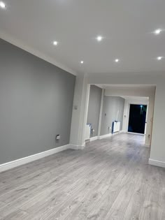 an empty room with hard wood floors and gray walls