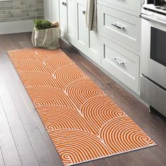 an orange and white rug in a kitchen next to a stove top oven with pots on the counter