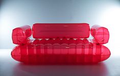 a red couch sitting on top of a white table next to a light up wall