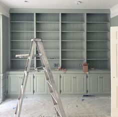 a ladder is in the middle of a room with built - in bookshelves