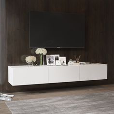 a white entertainment center with flowers and pictures on the wall next to a flat screen tv