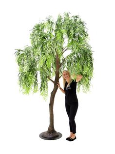 a woman standing next to a fake tree