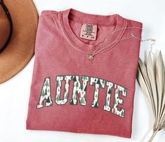 You will love our Comfort Colors Christmas auntie shirt! It is the perfect shirt for new aunts to wear during the holidays and makes a great Christmas pregnancy reveal to sister! PRODUCTION TIME: 1-3 business days  SHIPPING TIME: 2-5 business days  PRODUCT DESCRIPTION: These ultra soft pigment dyed shirts are one of our best sellers, 100% Cotton. 100% ring spun cotton Preshrunk, soft-washed, garment-dyed fabric Set-in sleeves Double-needle stitched sleeves and bottom hem Twill taped shoulder-to-shoulder 1" ribbed collar with double-needle topstitched neckline * For T-shirt Sizes Please refer to the Listing Image. CARE INSTRUCTION: To keep your garment looking its best, please follow these simple care instructions: Turn the garment inside out before washing. Machine wash cold with similar c Christmas Pregnancy Reveal, New Aunt, Auntie Shirts, Christmas Pregnancy, Dye Shirt, Pregnancy Reveals, Perfect Shirt, Printing Methods, Twill Tape