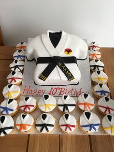 a birthday cake made to look like karate uniform with cupcakes on the table