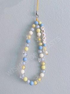 a beaded necklace hanging from a hook on a white wall with the word love spelled in small letters