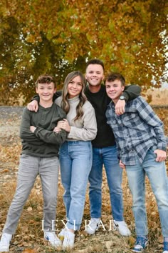 a family posing for a photo in front of some trees with their arms around each other