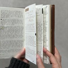 a person is holding an open book in their left hand and reading it with both hands