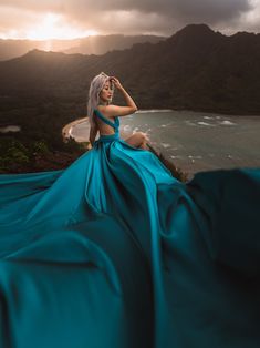 a woman in a blue dress sitting on top of a hill