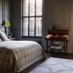 a bed sitting in a bedroom next to a window with shutters on the windowsill