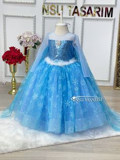 a blue dress with snowflakes on it and a flower vase in the background