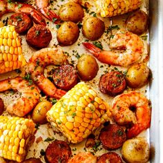 shrimp, corn on the cob and potatoes in a baking pan with parsley