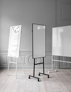 an easel stands next to a white board on wheels in the middle of a room