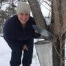 a woman standing next to a tree in the snow