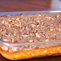 a casserole dish filled with food sitting on top of a wooden table next to a glass container