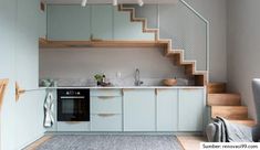 a kitchen and living room with stairs leading up to the upper floor