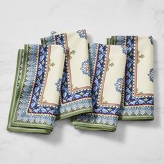 four blue and green napkins sitting on top of a white countertop next to each other