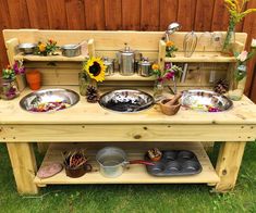 an outdoor kitchen with pots and pans on the stove top in front of a wooden fence