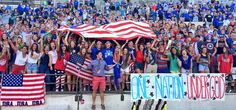 a group of people holding american flags in front of a crowd at a sporting event