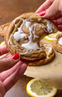 a person holding a cookie with icing and lemon slices