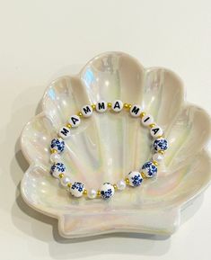 a white shell with blue beads and the word mama written on it in gold lettering