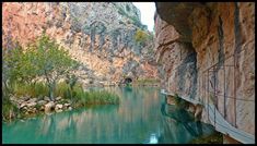 a river running through a canyon next to a cliff