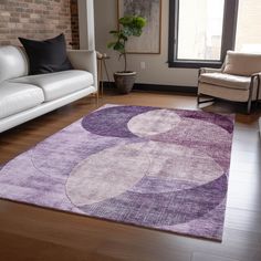 a living room filled with furniture and a purple rug on top of a hard wood floor