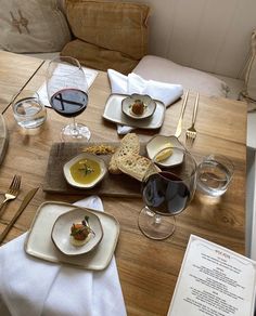 a wooden table topped with plates and glasses of wine