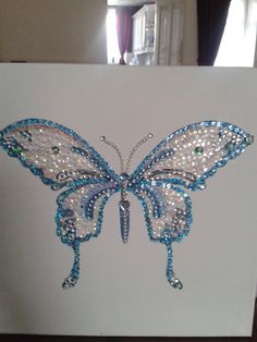 a white card with a blue butterfly made out of beads on it's wings