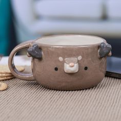 a coffee mug with a bear face on it and some crackers next to it