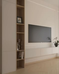 an empty living room with a large flat screen tv on the wall and bookshelves