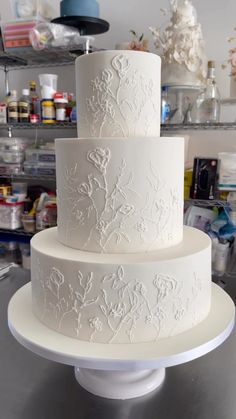 a three tiered white cake sitting on top of a metal table in a room