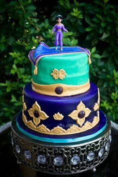 a three tiered cake sitting on top of a table next to green leaves and bushes