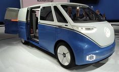 a blue and white car on display at an auto show with people in the back