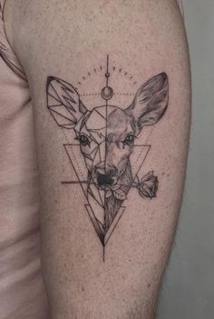 a deer tattoo on the left thigh with geometrical shapes and triangles around it's head