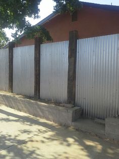 the side of a building that has some concrete blocks in front of it and trees on both sides