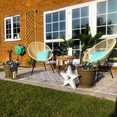 three chairs and two tables on a patio with potted plants in the foreground