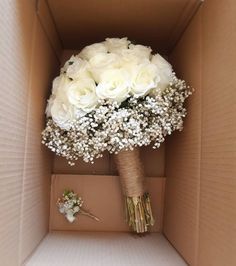 a bouquet of white roses and baby's breath in a cardboard box