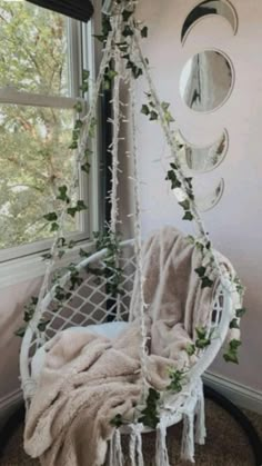 a white hanging chair in front of a window with plants growing on the seat and around it